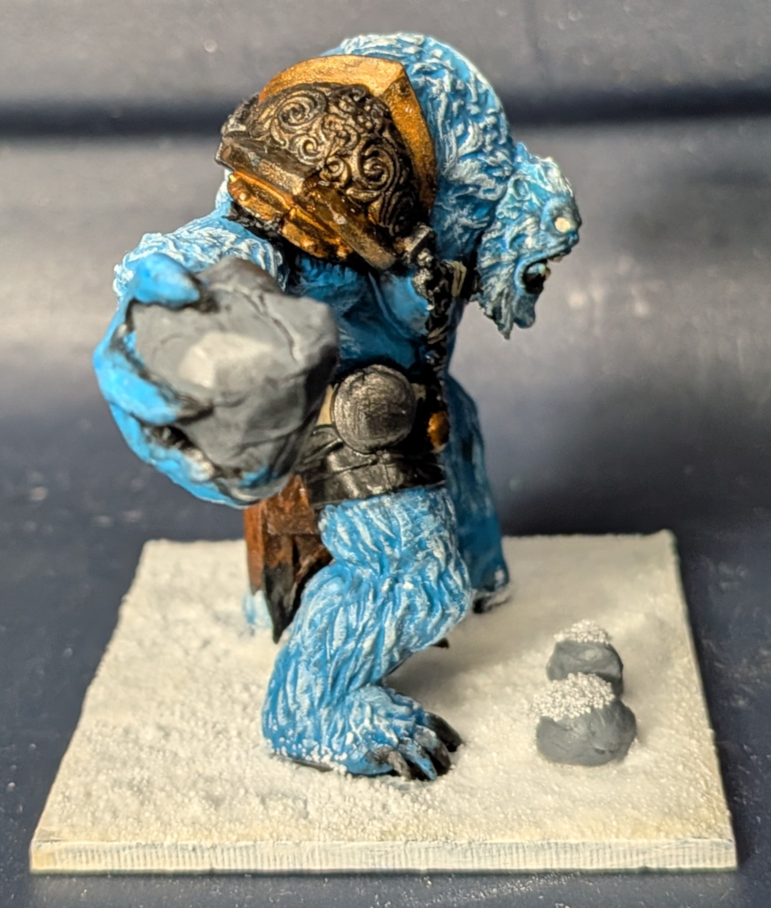 Right side view of Mantic Ice Troll painted blue with two additional rock markers on the base.