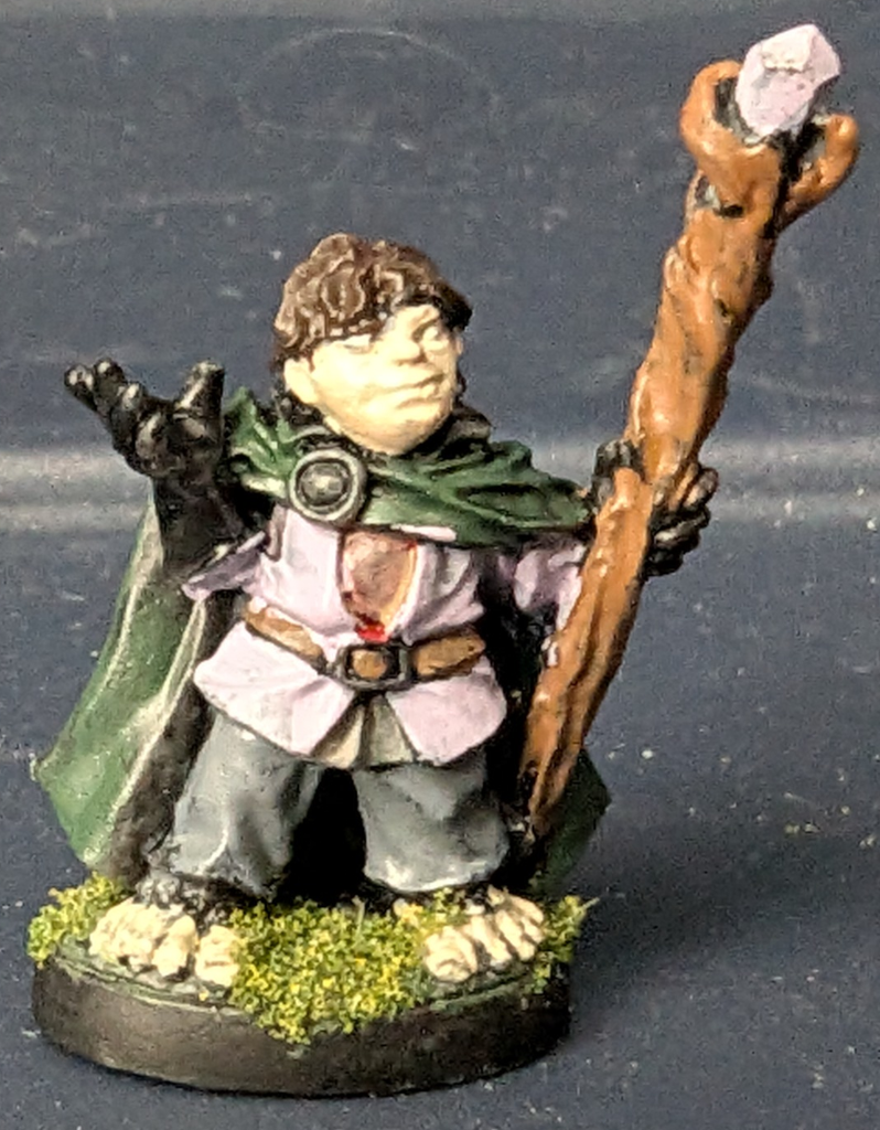 A barefoot halfling carrying a wooden staff with a crystal in his left hand.